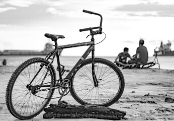 Fototapeta na wymiar Santa Marta, Colombia, May 17 2017 : Bike on the beach of Santa Marta, Colombia, with people and boats in the background.