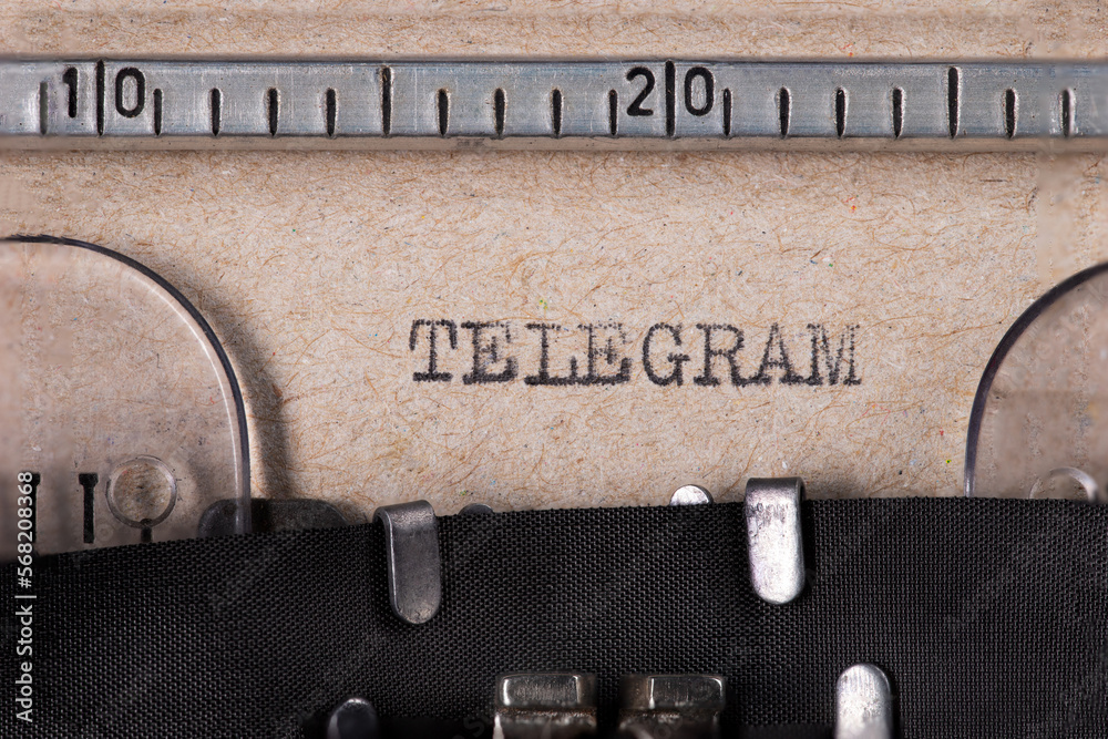 Fototapete the word 'telegram' embossed on gray paper using an old typewriter.