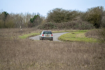 silver Skoda yeti motor car driving around a bend in the road on a country lane across Salisbury Plain