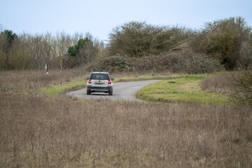 Obraz na płótnie Canvas silver Skoda yeti motor car driving around a bend in the road on a country lane across Salisbury Plain