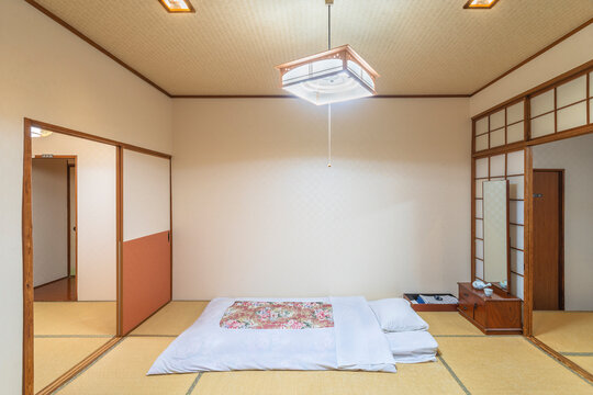 A typical traditional Japanese bedroom characterized by tatami mats, shoji doors, fusuma walls, futon mattress and minimalist decorations, creating a peaceful and serene atmosphere.