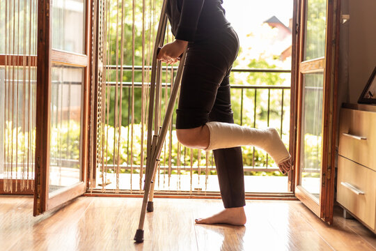 Close-up of a woman with a broken ankle, standing by the living room door
