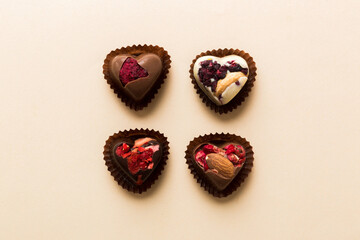chocolate sweets in the form of a heart with fruits and nuts on a colored background. top view with space for text, holiday concept