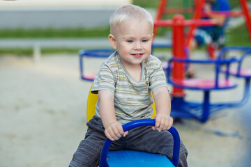 Cute kid having fun on seesaw at playground. Concept of kindergarten.