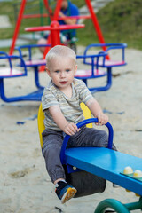 Fototapeta na wymiar Cute kid having fun on seesaw at playground. Concept of kindergarten. Vertical
