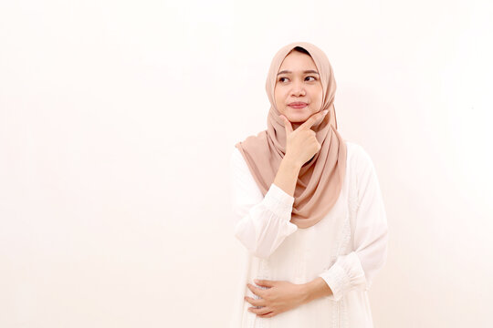 Portrait of young asian muslim woman standing while glancing sideways on blank space. Isolated on white