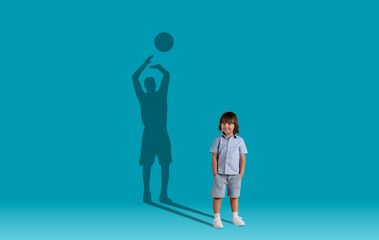Cute little boy and shadow of adult basketball player behind