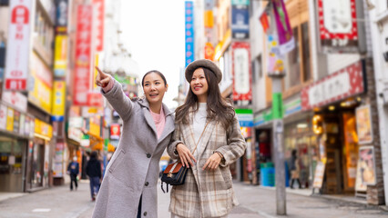Asian woman friends shopping together at Shibuya district, Tokyo, Japan with crowd of people...
