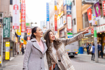 Asian woman friends shopping together at Shibuya district, Tokyo, Japan with crowd of people walking in the city. Attractive girl enjoy and fun outdoor lifestyle travel city in autumn holiday vacation