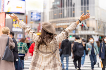 Happy Asian woman shopping and crossing street crosswalk with crowd of people at Shibuya, Tokyo,...