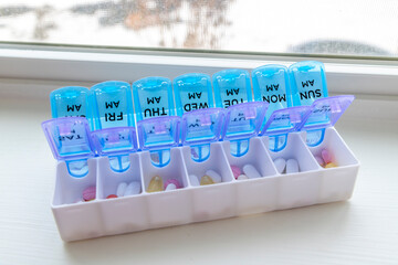 A full pill box or vitamin organizer with the days of the week separated individually by am and pm to help remind when medication should be taken. - obrazy, fototapety, plakaty