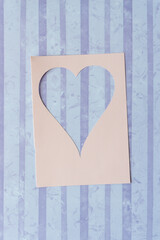 pink paper stencil card with heart shape cutout on violet scrapbook paper with stripes