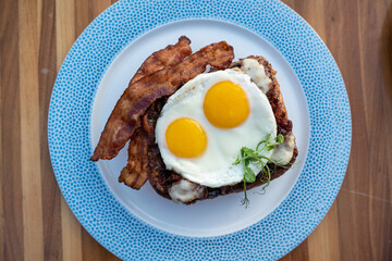 Classic french toast with Nueske bacon and sunny side up eggs on plate setting