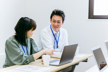 Fototapeta na wymiar 会社のオフィスでパソコンを使って笑顔で企画・アイディア・提案・分析の会議をする男女（ビジネス） 