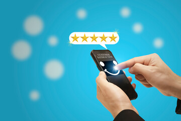 Businessman hand using smartphone pressing smile icon on the screen with popup gold five-star icon for rating feedback review satisfaction service for giving best score point, Customer survey.