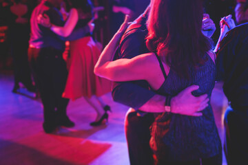 Couples dancing traditional latin argentinian dance milonga in the ballroom on a festival, tango studio, salsa, bachata and kizomba lesson in the red and purple lights, rehearsal in the dance class - obrazy, fototapety, plakaty