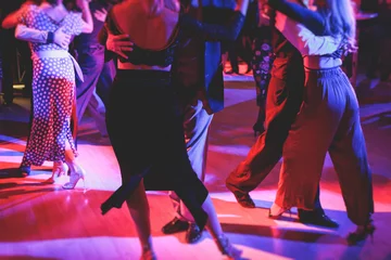 Photo sur Plexiglas Anti-reflet École de danse Couples dancing traditional latin argentinian dance milonga in the ballroom on a festival, tango studio, salsa, bachata and kizomba lesson in the red and purple lights, rehearsal in the dance class