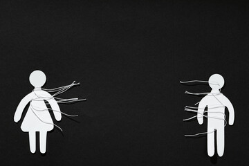 Divorce concept. Paper human figures with cut white threads on black background, flat lay. Space...