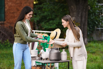 Women shopping at table in yard. Garage sale