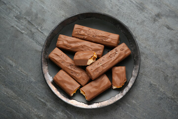 Plate with delicious chocolate bars on black table, top view