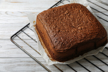 Homemade chocolate sponge cake on white wooden table, closeup. Space for text