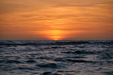 Obraz premium Ocean sunset. Big white sun on dramatic bright sky background, soft evening horizont over sea dark water