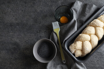 Homemade braided bread and ingredients on grey table, flat lay with space for text. Cooking traditional Shabbat challah