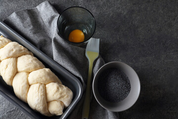 Homemade braided bread and ingredients on grey table, flat lay with space for text. Cooking traditional Shabbat challah