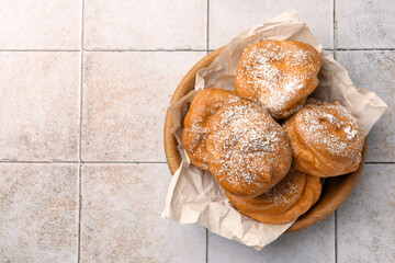 Delicious profiteroles with powdered sugar on white tiled table, top view. Space for text