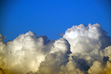 White fluffy cumulonimbus clouds forming before thunderstorm on summer blue sky. Changing stormy...