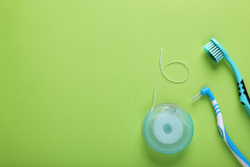 Flat lay composition with dental floss and different teeth care products on green background, space...