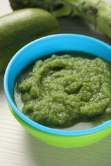 Healthy baby food. Bowl with tasty broccoli puree on white wooden table