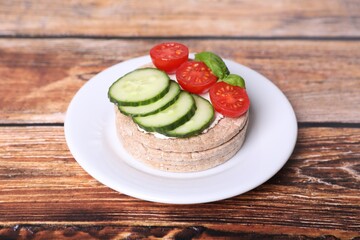 Tasty crispbreads, cucumber, tomatoes, cream cheese and basil on wooden table, closeup