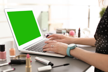 Fototapeta premium Young woman using laptop at desk, closeup. Device display with chroma key