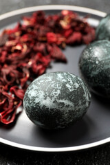 Naturally painted Easter eggs on black table, closeup. Hibiscus used for coloring