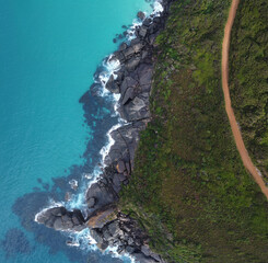 Amazing aerial View of the coast of Shelleys beach with blue sea, green trees and red gravel road...