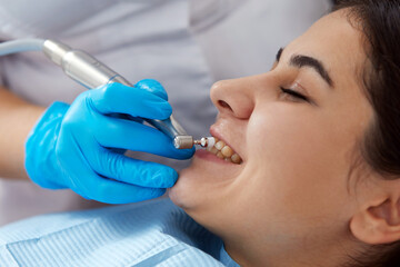 Young woman getting her teeth polished in dental clinic. Professional dental cleaning concept