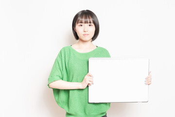 Fototapeta premium 大きいスケッチブックを見せる若い女性