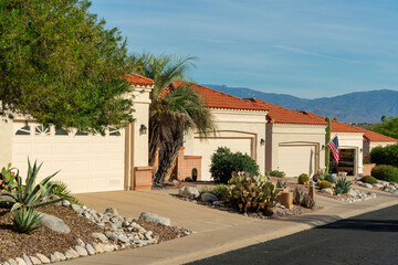 Row of modern adobe style one story houses in desert community of arizona with visible garage doors...