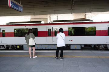 Asian young woman waiting the train in the platform of subway station and move of the train. Public transport concept.