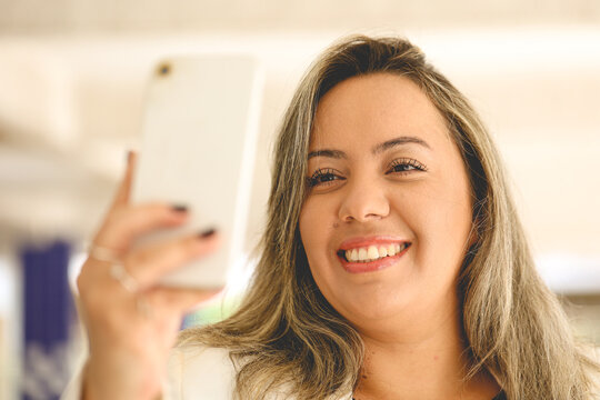 Uma mulher de negócios feliz e sorrindo que está segurando um telefone celular para fazer uma selfie. 