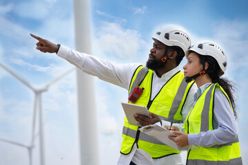 Engineer male and female on wind turbine farm. Two engineers discussed the plan for the maintenance of wind turbines.
