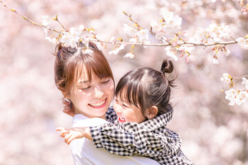 満開の桜の中、娘を抱く母親