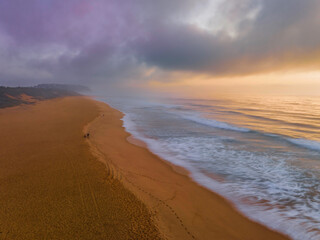 Summer sunrise fog descends over the headland at the beach