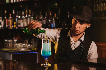 bartender mixes a Blue Lagoon cocktail in a glass at bar counter in restaurant