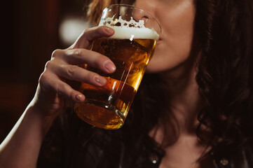 woman sexually drinks from a glass of beer lager with foam close-up