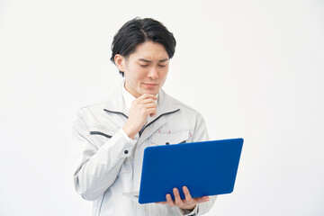 Obraz premium パソコンを持って考える作業着の男性 白背景