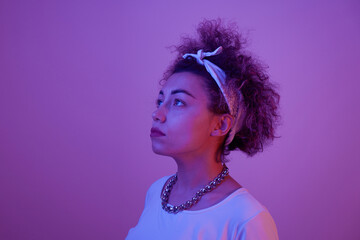 Close-up face portrait of cool kazakh model girl with curls and chain in neon light isolated on...