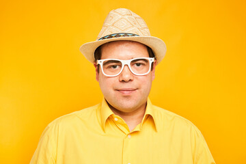 Portrait of positive fat man in hat kindly smiling isolated on yellow studio background, travel vacation concept