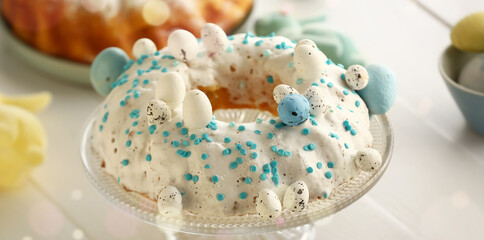 Dessert stand with tasty Easter cake and eggs on white wooden table, closeup